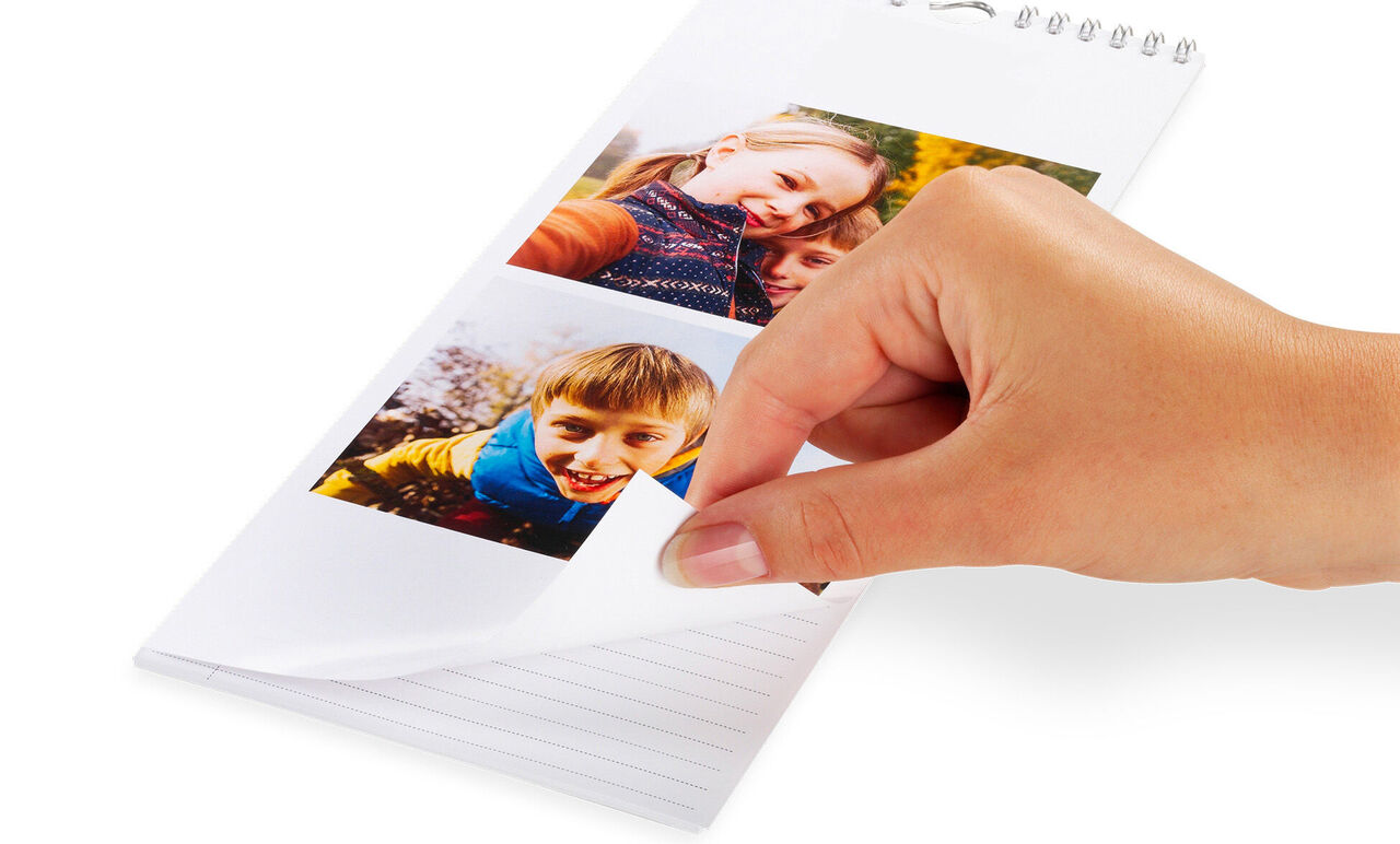 Une main feuillette un calendrier photo avec deux photos.