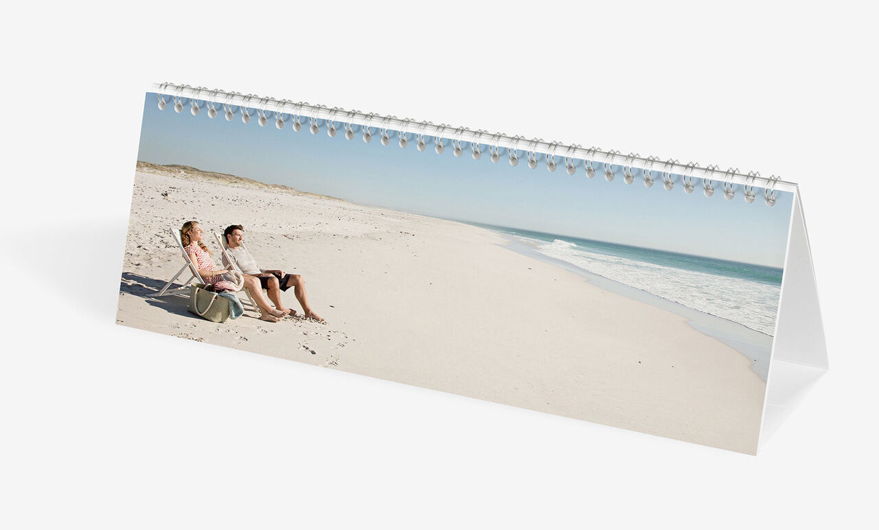 Un couple profite ensemble du coucher de soleil à la plage dans le calendrier photo CEWE