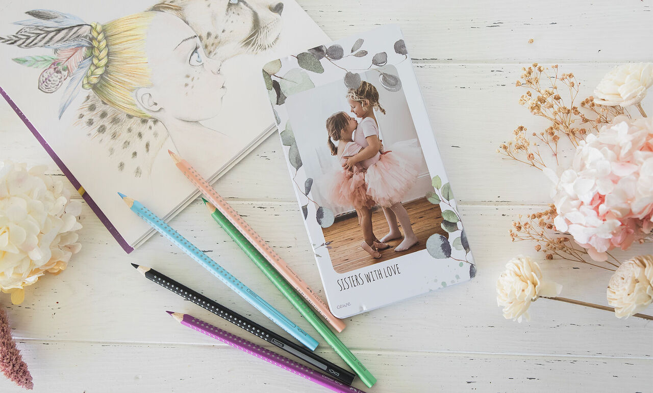 Boîte métallique de crayons de couleur avec photo de deux sœurs en robe rose sur le couvercle.