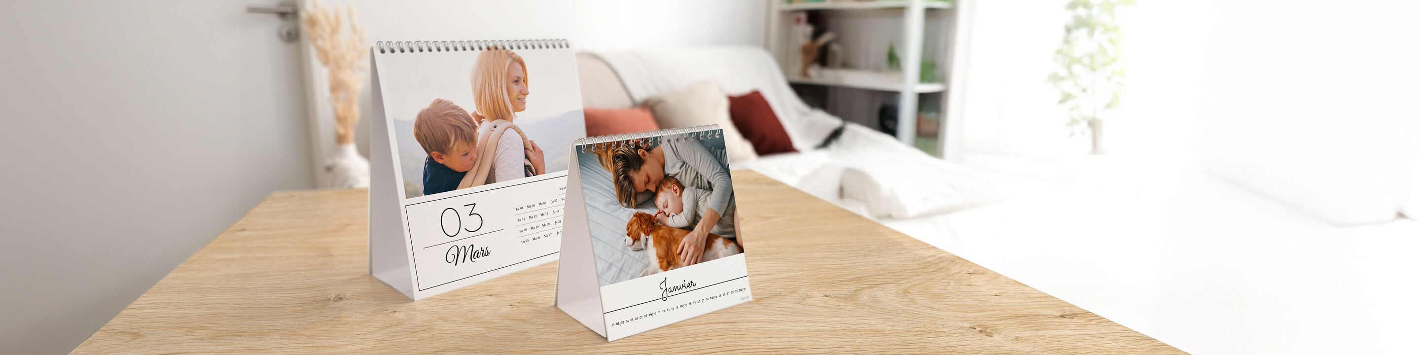 Deux calendriers CEWE sur une table en bois. L'un montre un enfant avec une mère, l'autre un chien avec un humain.